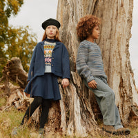 Two children sitting on a tree stump in a natural setting