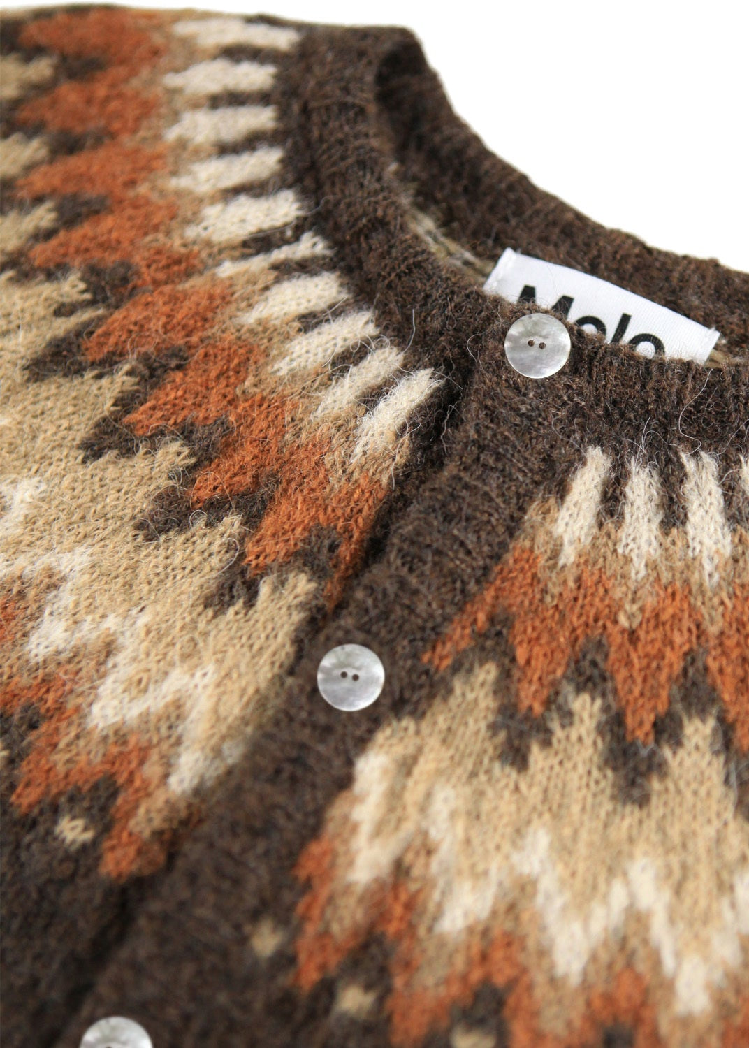Close-up of a patterned sweater with buttons and a visible brand label.