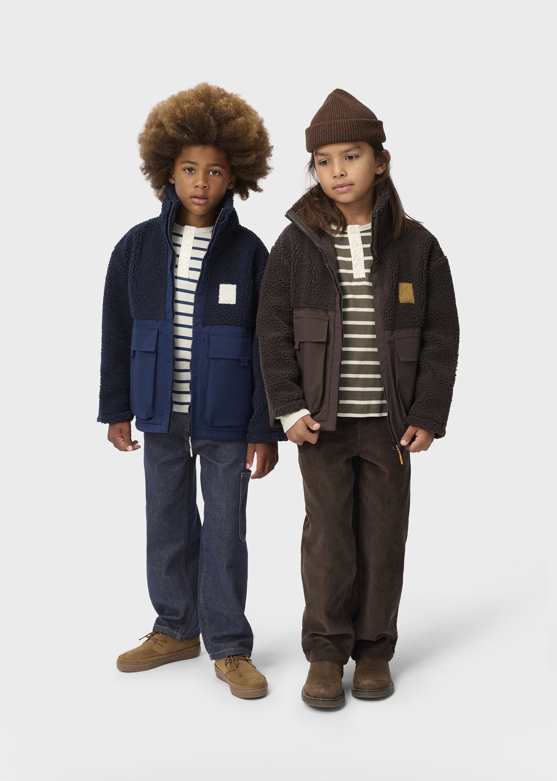 Two children wearing matching jackets and striped shirts on a white background
