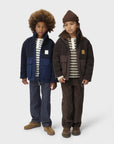 Two children wearing matching jackets and striped shirts on a white background