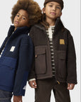 Two children wearing jackets standing side by side against a white background