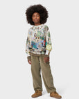 Person wearing a patterned sweater and beige pants on a white background