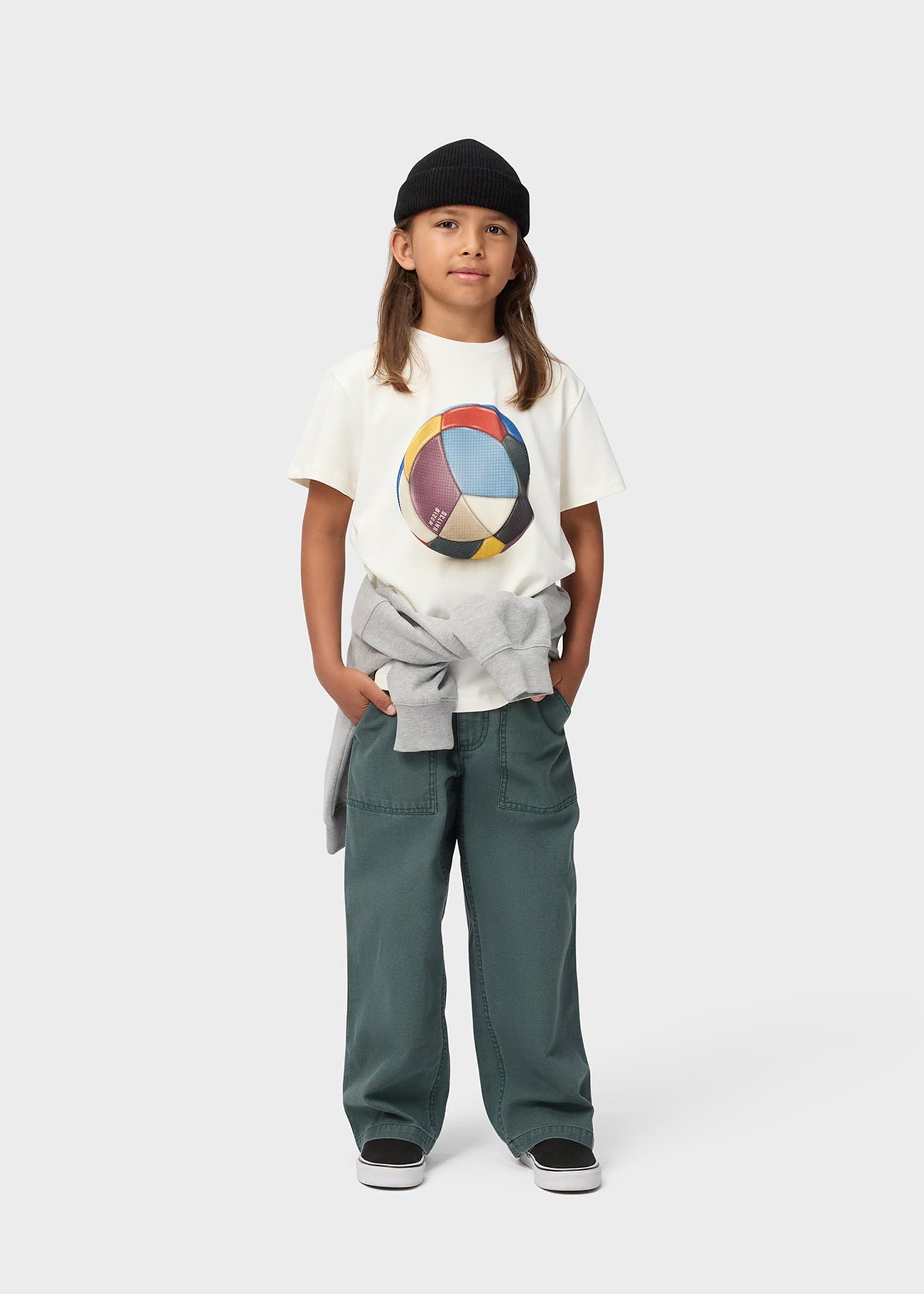 Child wearing a white t-shirt with a colorful graphic and gray pants on a white background