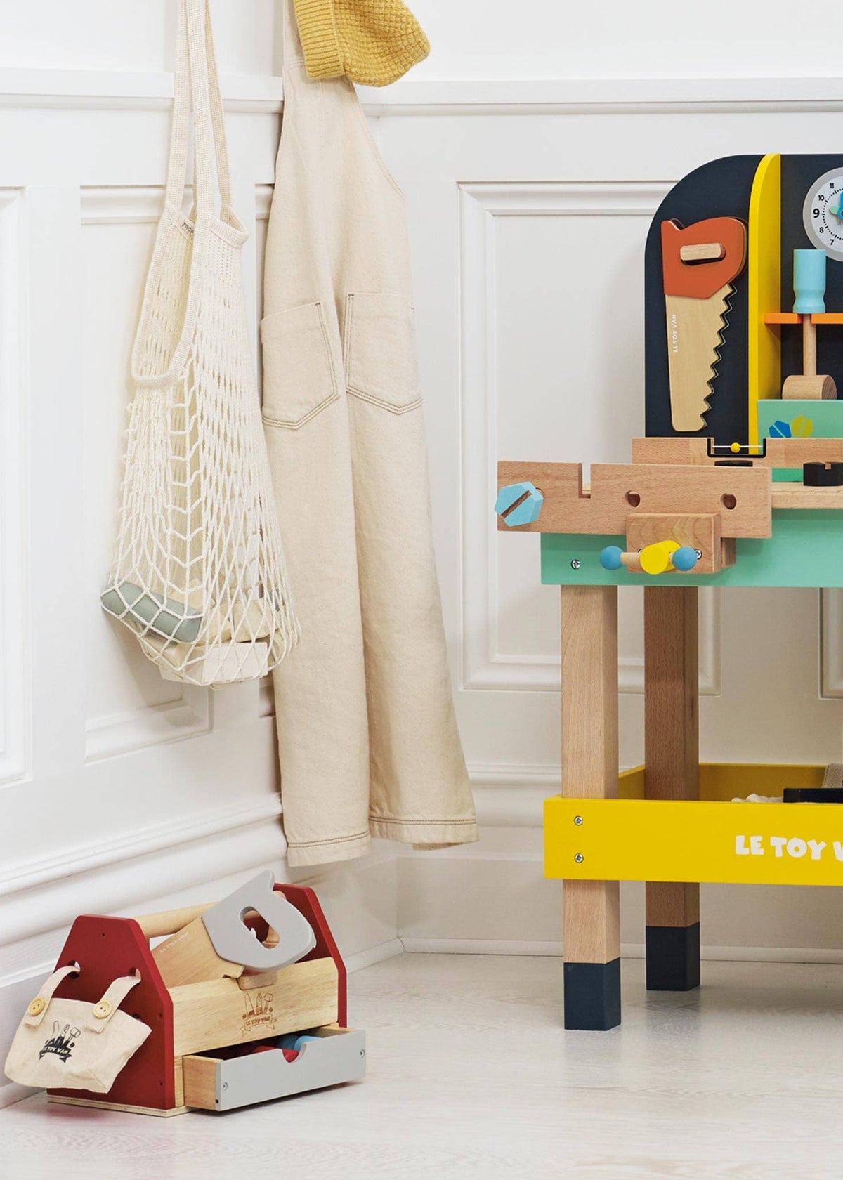 Children's toy workbench with tools and a toolbox on a white floor.