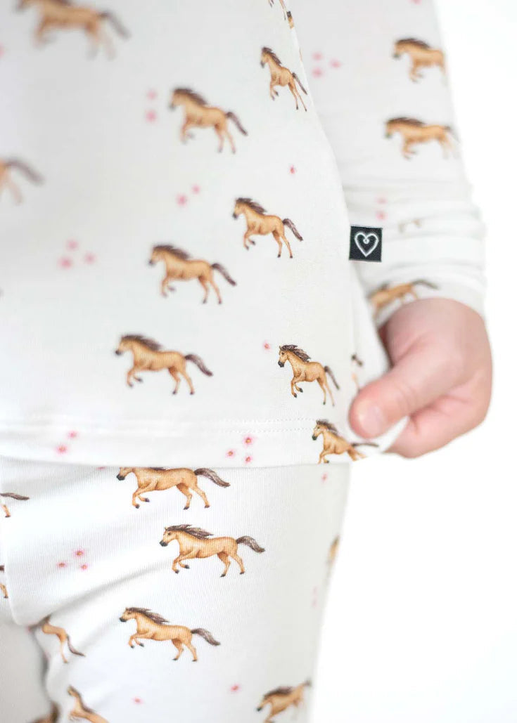 Children's onesie with horse pattern held by a hand