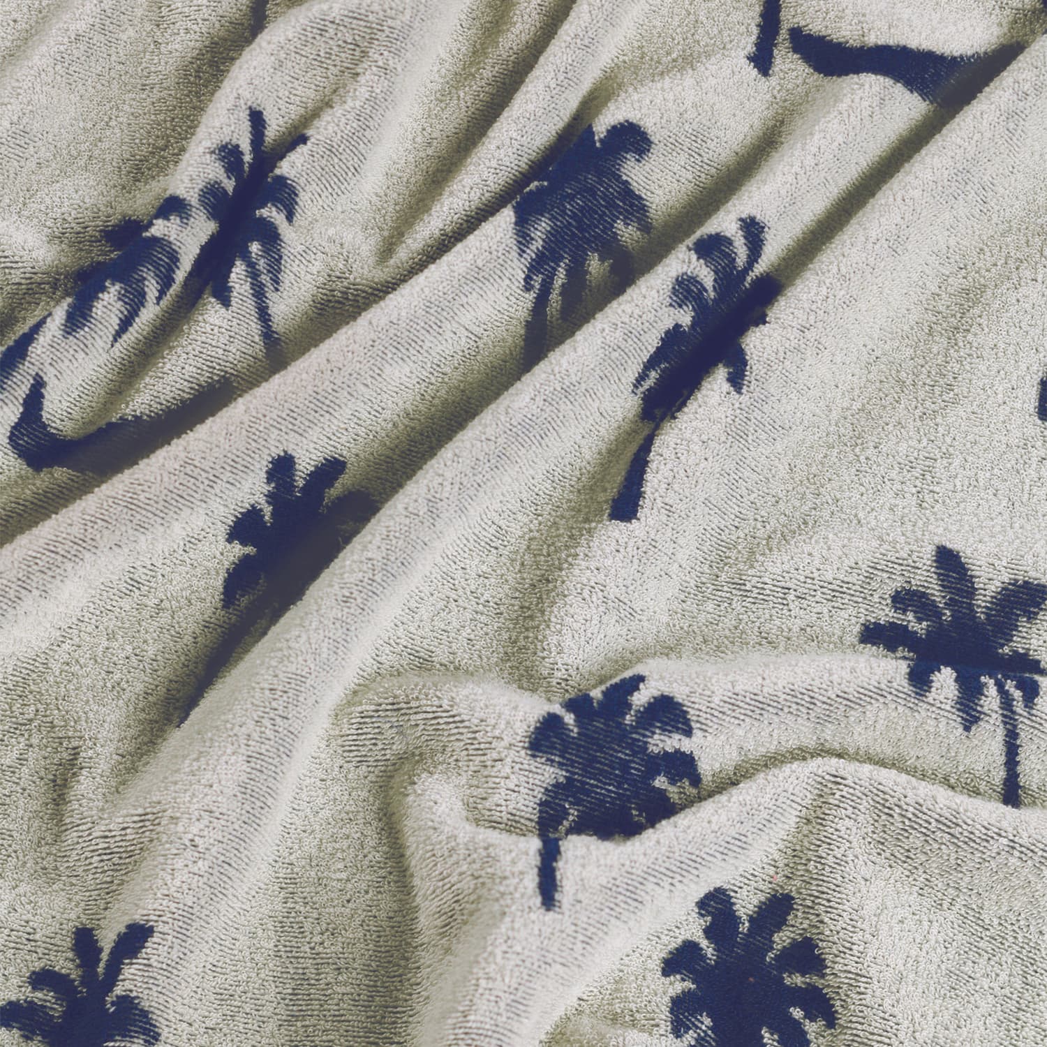 Close-up of a textured fabric with navy palm tree patterns on a beige background