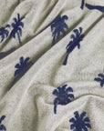 Close-up of a textured fabric with navy palm tree patterns on a beige background