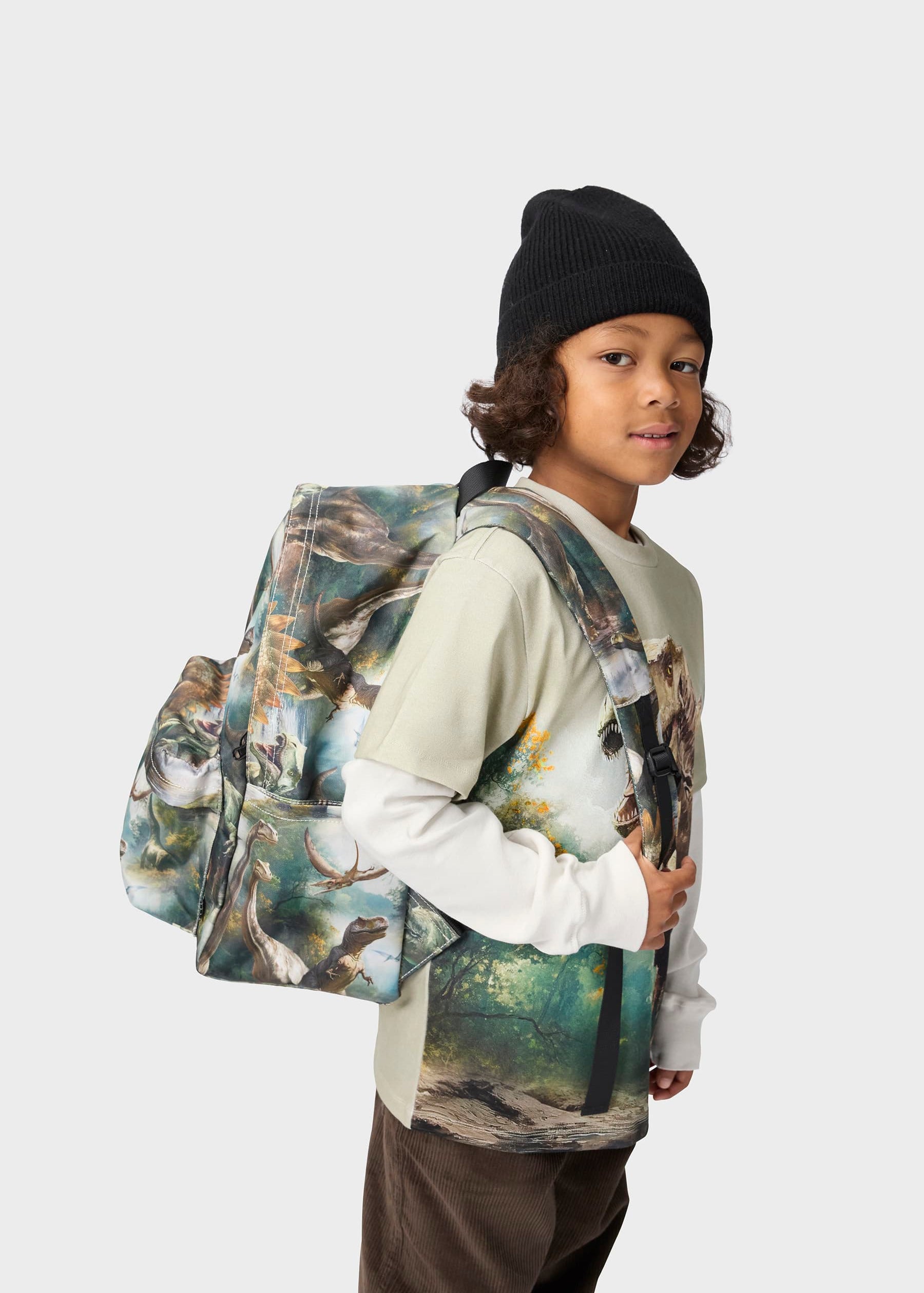 Child wearing a backpack with a nature design on a plain background