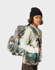 Child wearing a backpack with a nature design on a plain background
