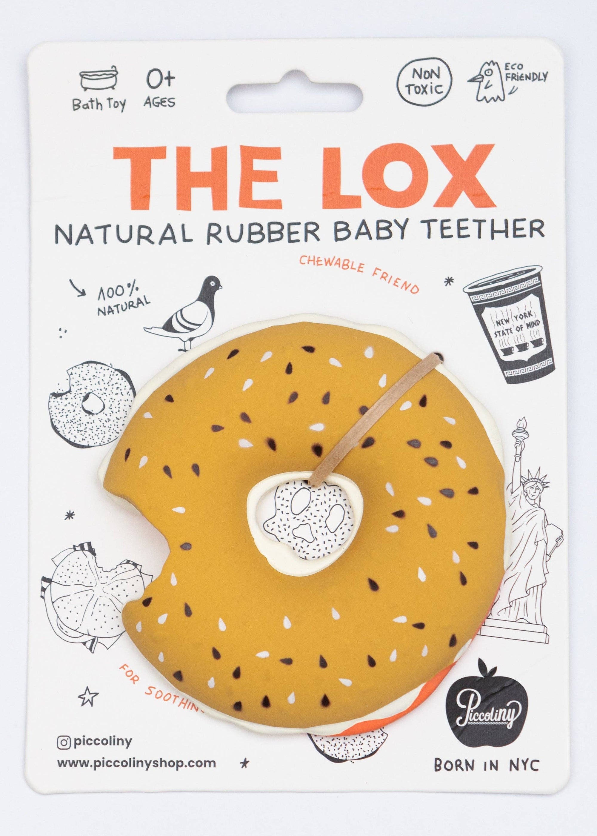 A packaged baby teether shaped like a donut, with a mustard-yellow surface, white sesame-seed pattern, and a small wooden stick handle. The item is mounted on a white printed backing card with orange and black text reading 'THE LOX' and 'NATURAL RUBBER BABY TEETHER,' plus illustrated doodles and a 'Peculiarity' logo.