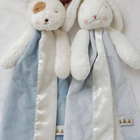Two plush toys with blue and white scarves on a light background