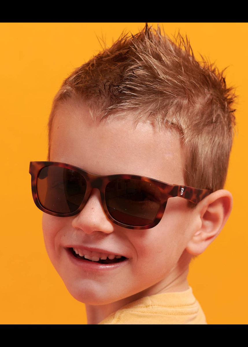 Child wearing sunglasses with a bright orange background