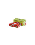 Red toy car with wooden wheels next to its packaging box on a beige background