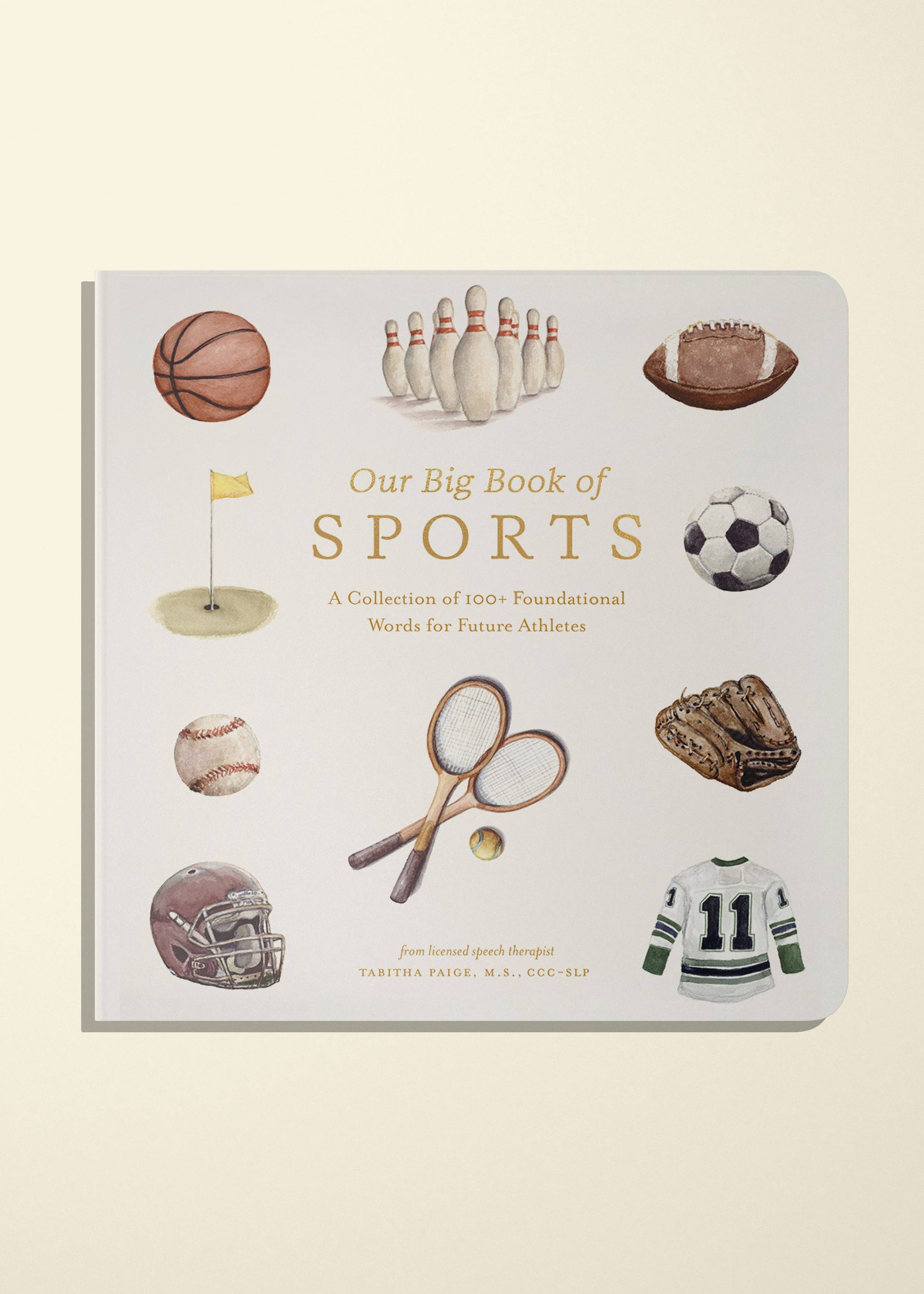 Our Big Book of Sports children's book with a white cover featuring watercolor illustrations of various sports items, photographed on a light cream background.