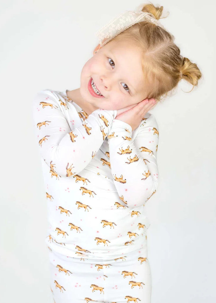Child wrapped in a white blanket with gold animal patterns on a plain background