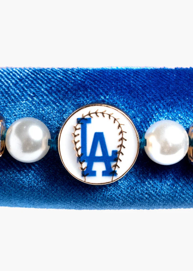 Blue bracelet with pearls and a baseball team logo charm on a white background