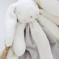 White plush bunny toy with a soft blanket in a woven basket