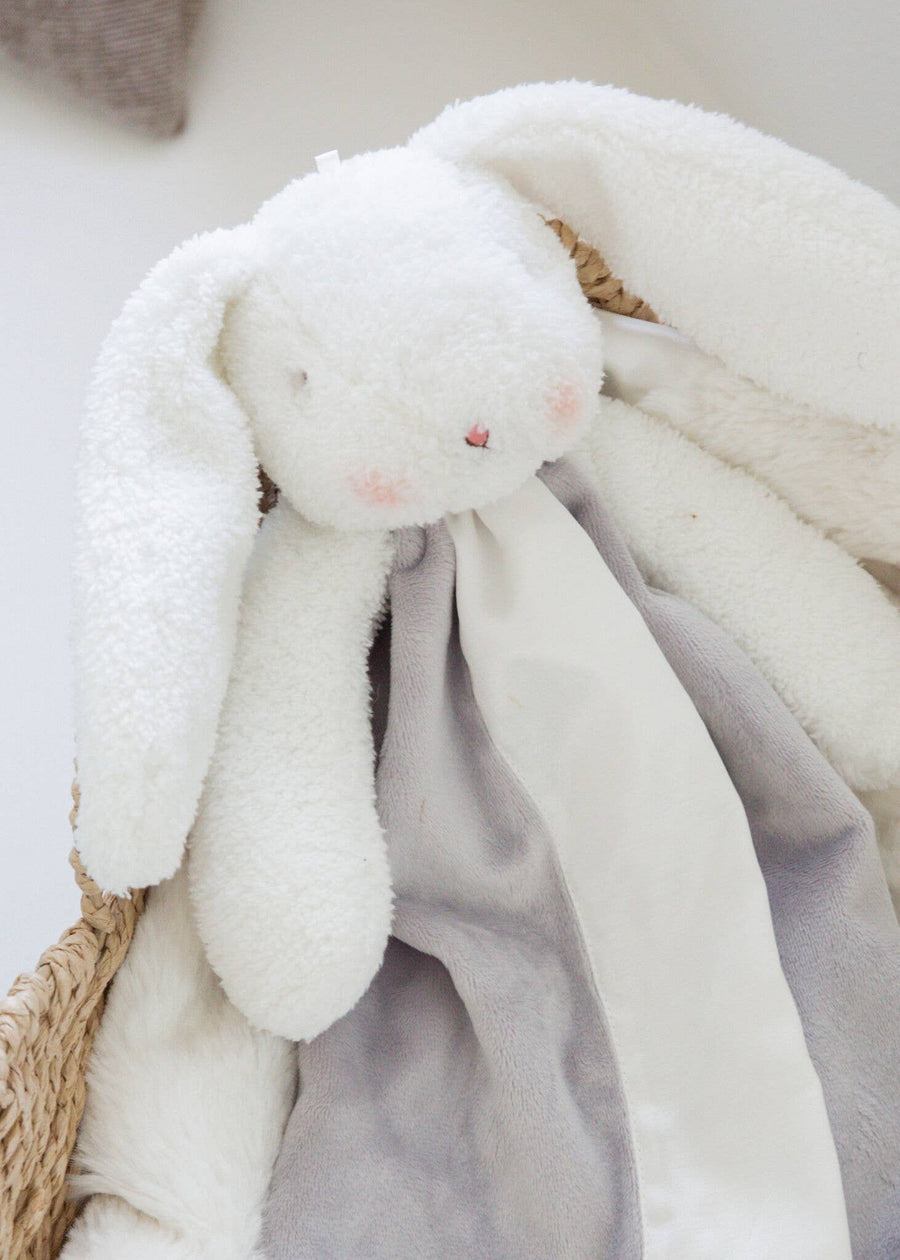 White plush bunny toy with a soft blanket in a woven basket