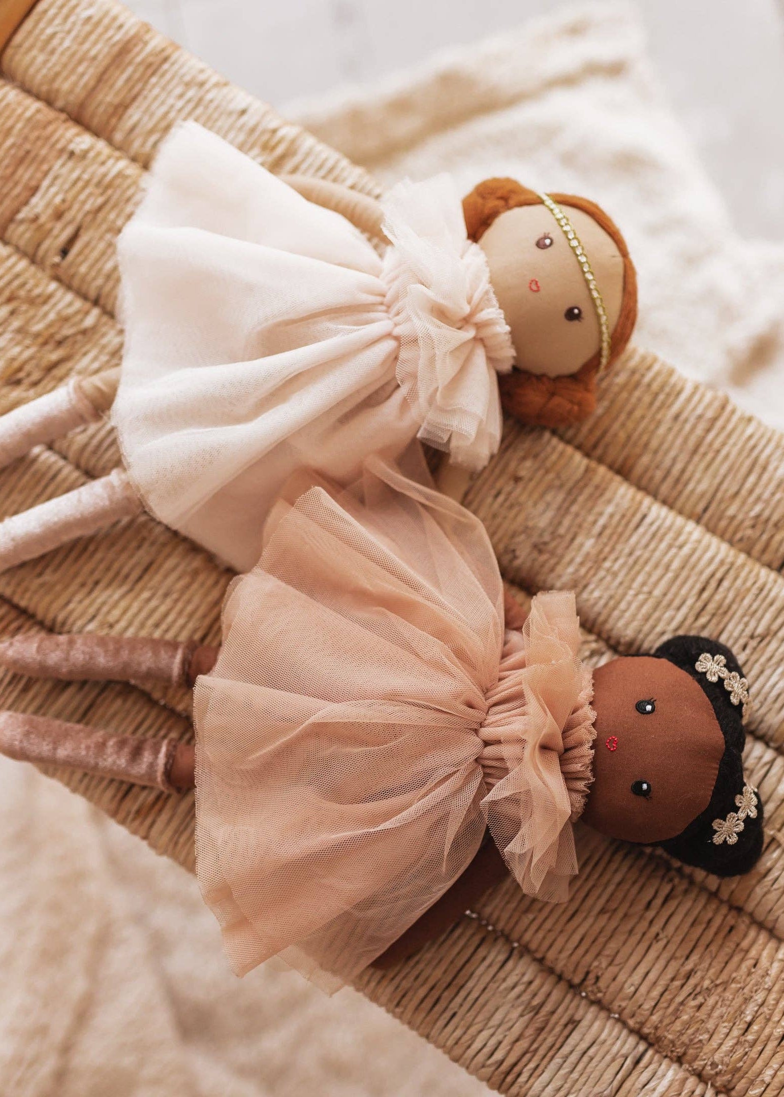 Two dolls with tulle dresses on a textured surface