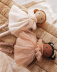 Two dolls with tulle dresses on a textured surface