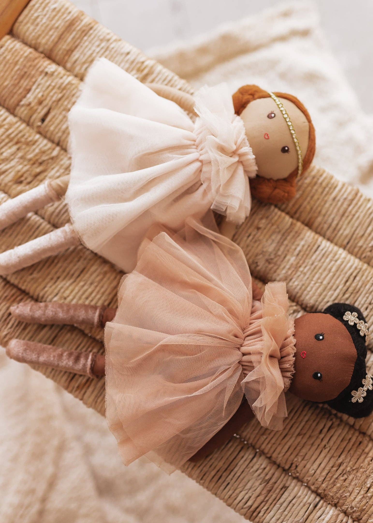 Two dolls with tulle dresses on a textured surface