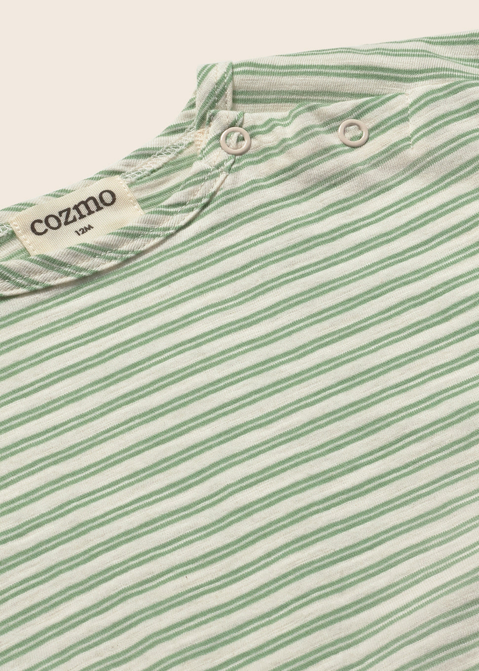 Close-up of a green and white striped shirt with 'cozmo' branding on a light background