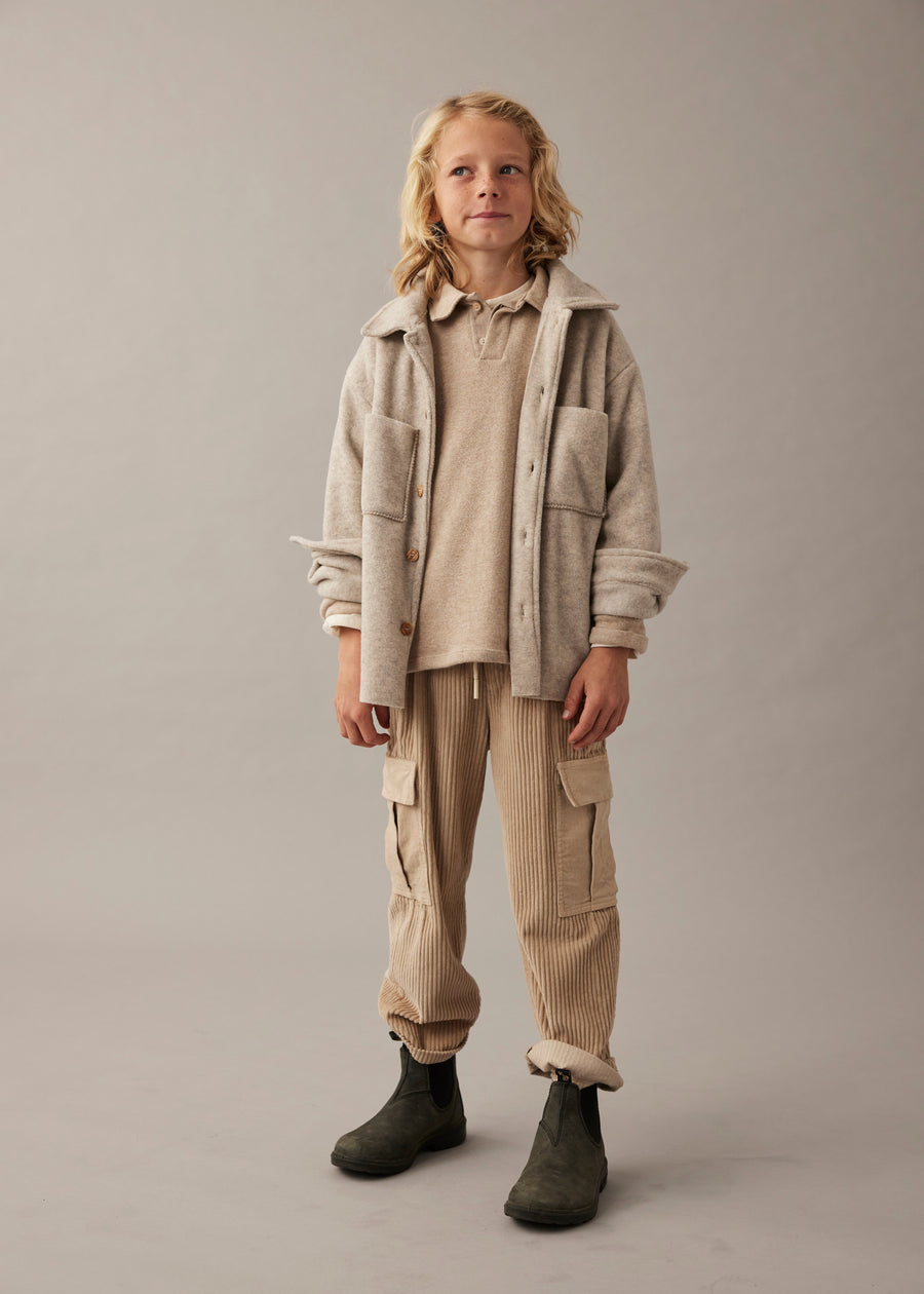 Child wearing a beige jacket and pants on a plain background