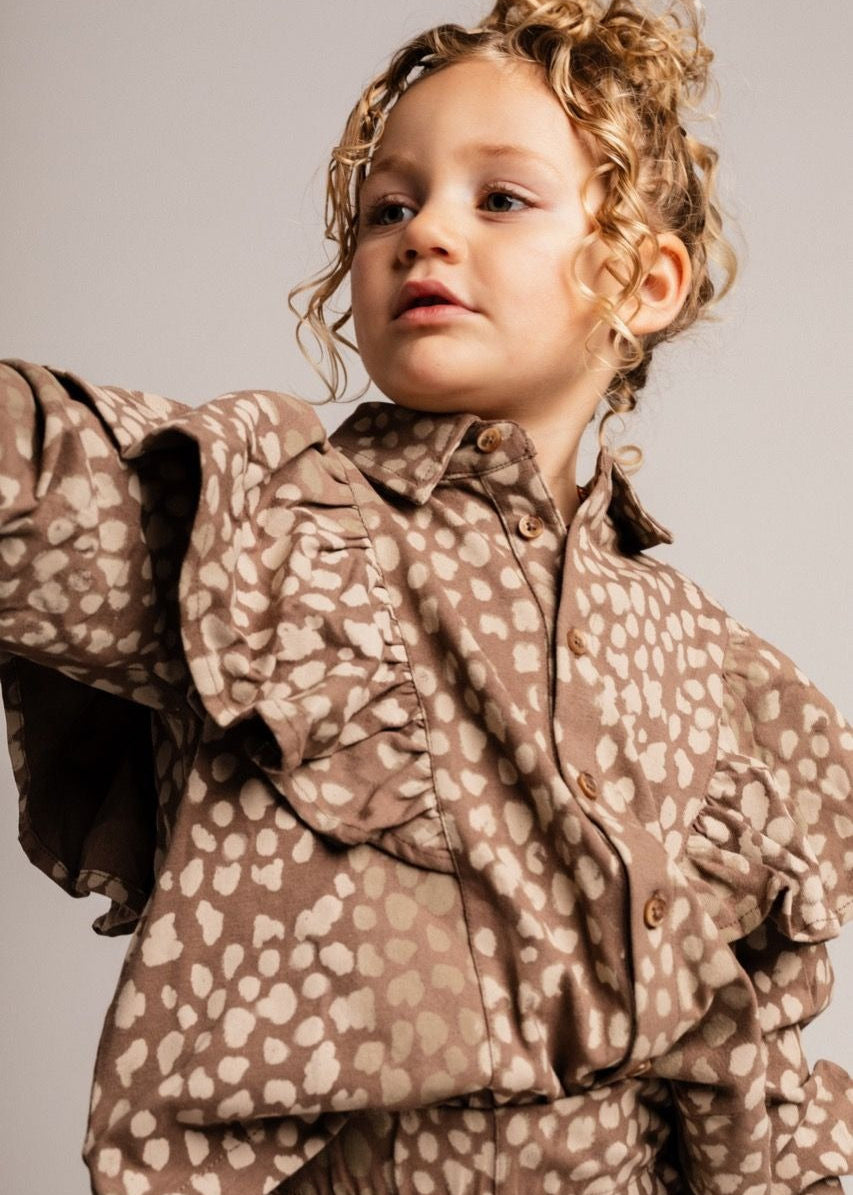 Child wearing a brown patterned outfit against a plain background