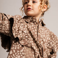 Child wearing a brown patterned outfit against a plain background