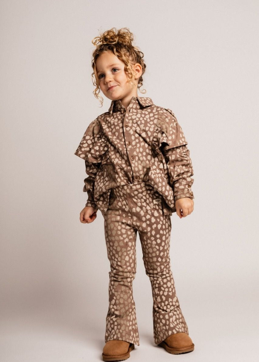 Child wearing a brown patterned outfit on a plain background