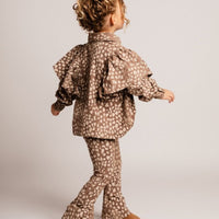 Child wearing a patterned outfit on a plain background