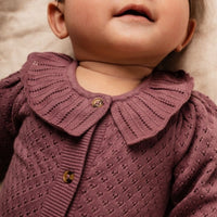Baby wearing a purple knitted cardigan with a collar