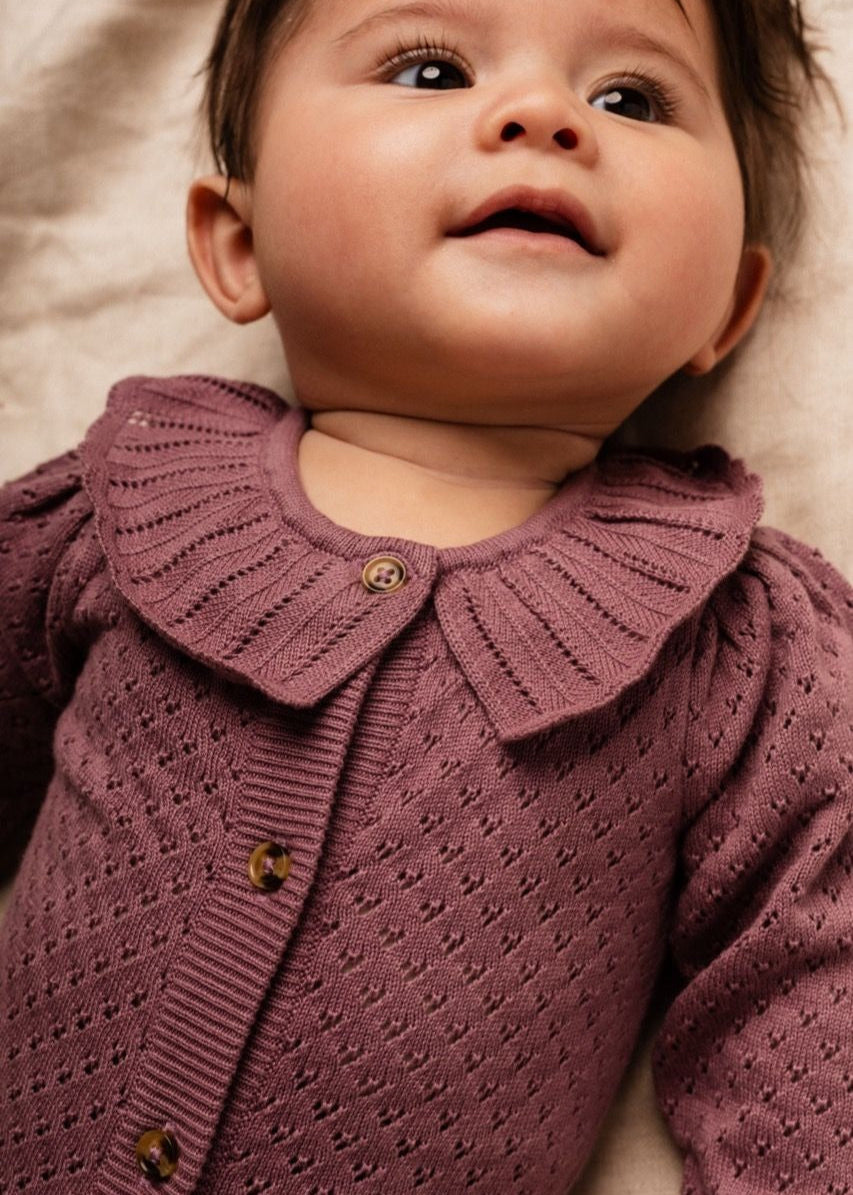 Baby wearing a purple knitted cardigan with a collar