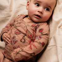 Baby wearing a floral long-sleeve shirt on a soft beige background