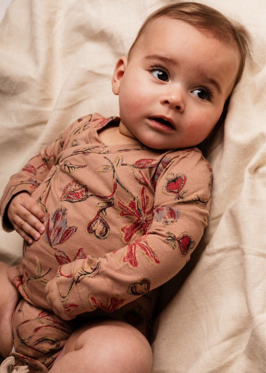 Baby wearing a floral long-sleeve shirt on a soft beige background
