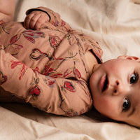 Baby lying on a soft surface wearing a floral outfit