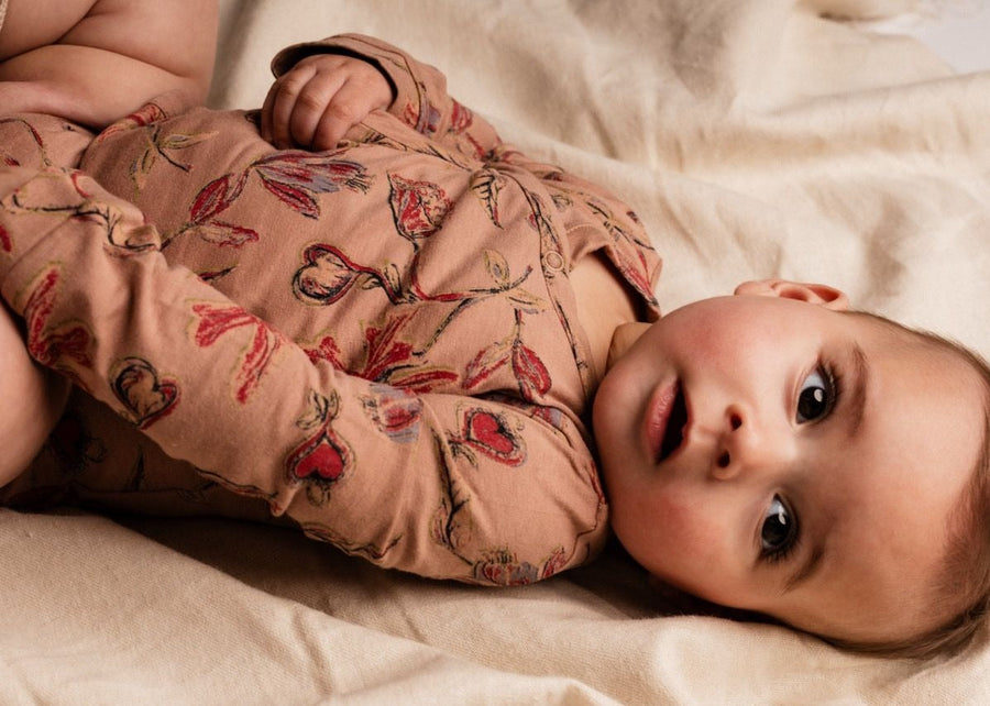 Baby lying on a soft surface wearing a floral outfit
