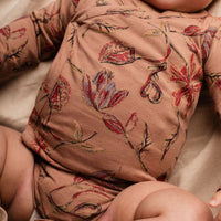 Baby wearing a floral-patterned outfit on a soft surface