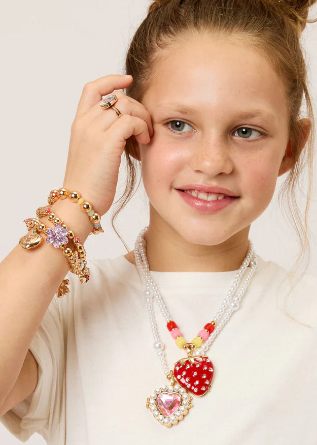 Young girl wearing a necklace with heart-shaped pendants on a plain background
