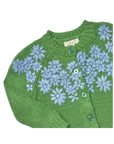 A close-up of a green knitted cardigan with light blue floral embroidery and green buttons, showing a pink and white brand label that reads 'PINK & DUFFLE'.
