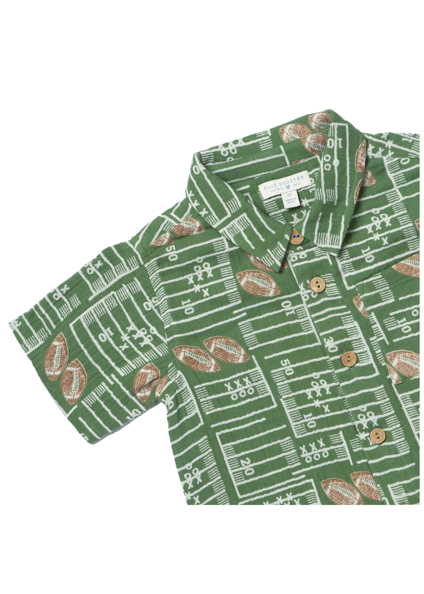 A green short-sleeve button-up shirt with a white football field and yard line pattern, accented with brown football motifs and brown buttons. The brand label reads 'The Happy Camp'.