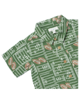 A green short-sleeve button-up shirt with a white football field and yard line pattern, accented with brown football motifs and brown buttons. The brand label reads 'The Happy Camp'.