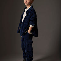 Young boy wearing a navy blue outfit against a gray background