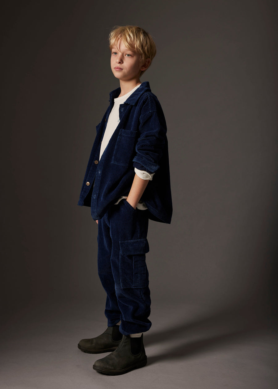 Young boy wearing a navy blue outfit against a gray background