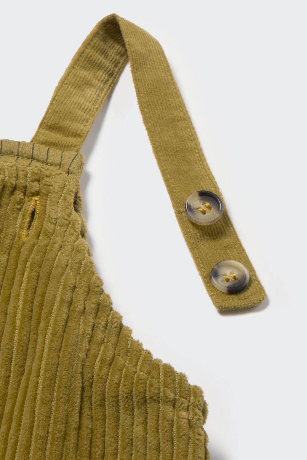 Green corduroy overalls with a strap and buttons on a white background