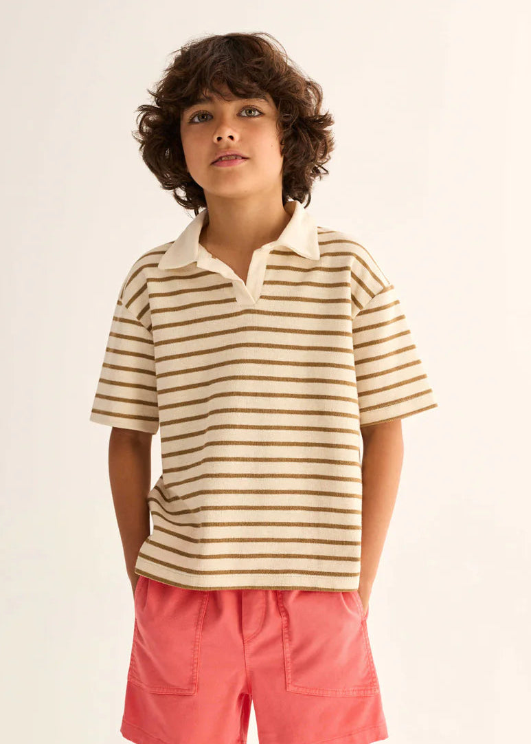 Child wearing a striped polo shirt and pink shorts on a white background