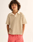 Child wearing a striped polo shirt and pink shorts on a white background