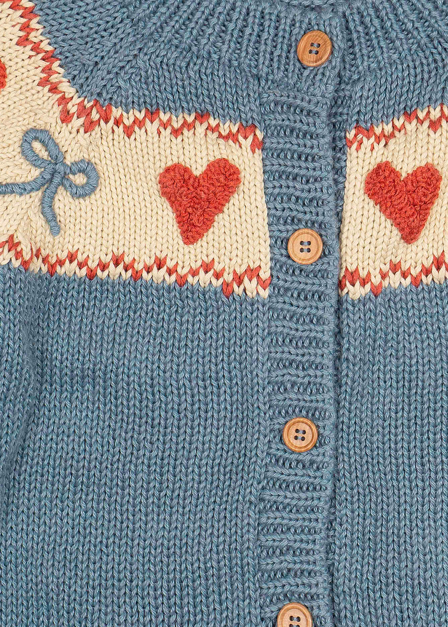 Knitted cardigan with heart and bow patterns on a blue background