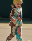 Child wearing a tie-dye outfit and yellow beanie on a basketball court