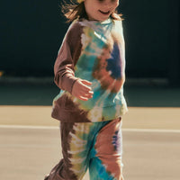 Child wearing a tie-dye outfit and yellow beanie on a basketball court